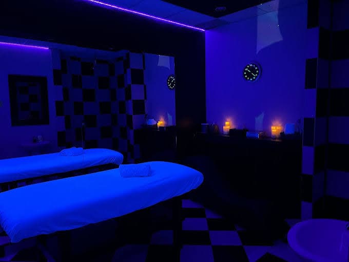 Private massage room with blue ambient lighting and candlelit atmosphere