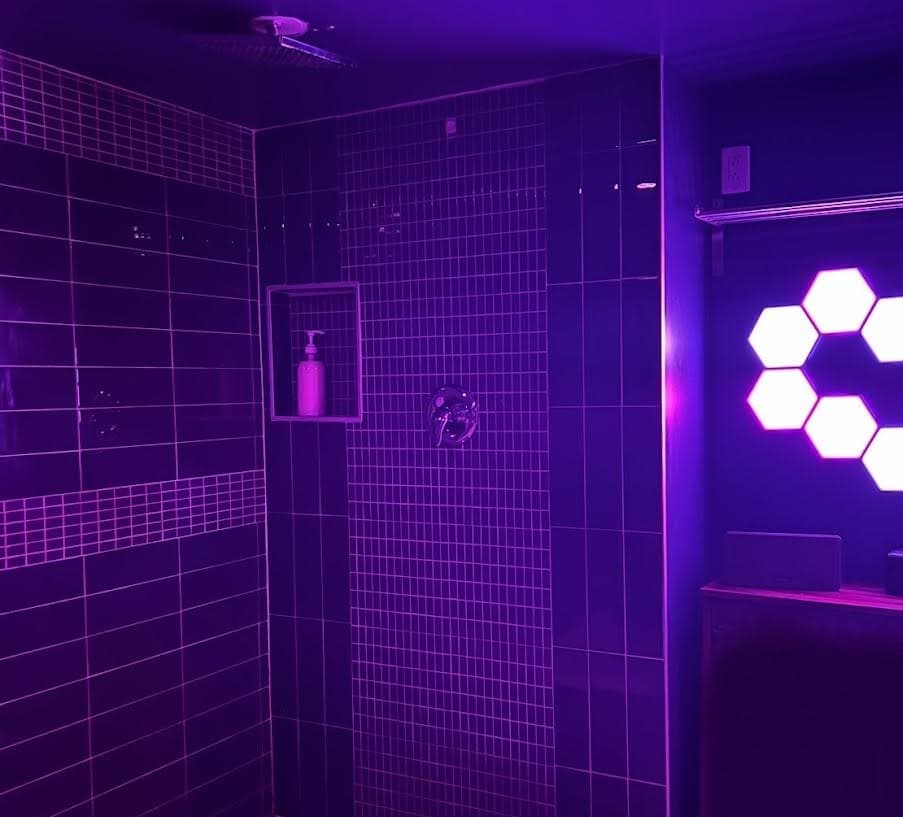 Modern shower suite with purple lighting and hexagonal wall lights