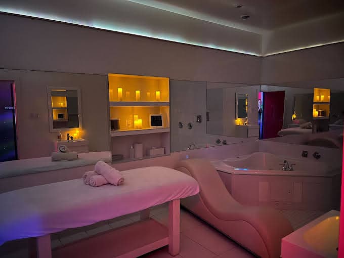 Massage table and jacuzzi in candlelit room with warm ambient lighting