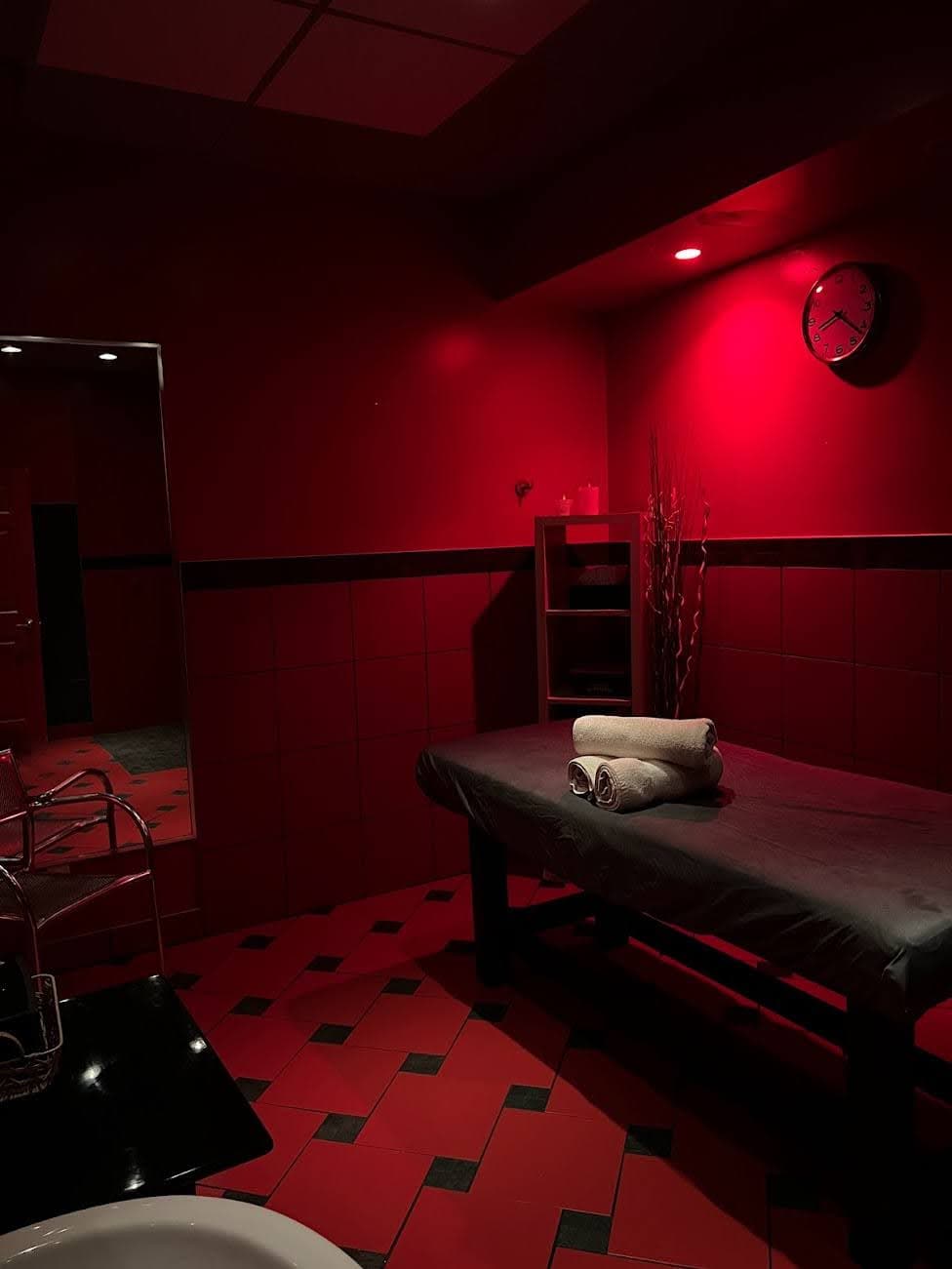 Red-themed massage room with towels and tiled floor at La Montrealaise